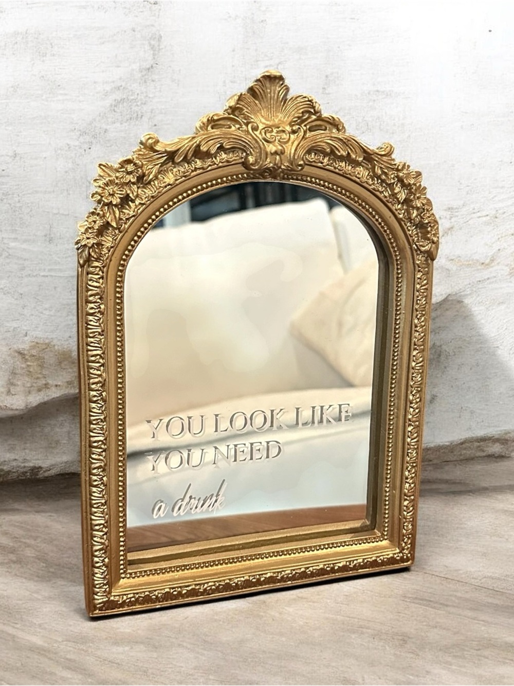Ornate Gold Arch Mirror With Playful Phrase “You Look Like You Need a drink”